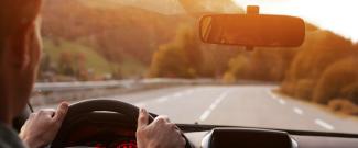 driver looking forward towards the road with their eyes reflected in the rearview mirror